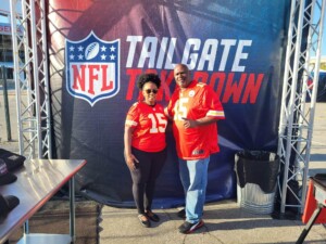 Shelia Johnson and Mike Powell pose in front of NFL's Tailgate Takedown sign
